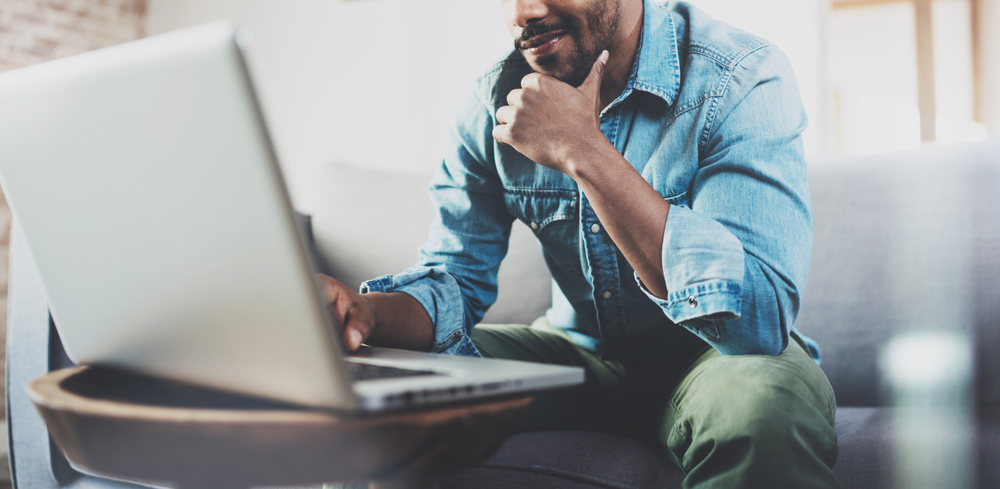 Smiling,Bearded,African,Man,Working,At,Home,While,Sitting,On